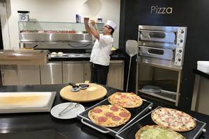 Koch in der Küche des Aphrodite Beach Club, der eine Pizza mit den Händen in der Luft formt.