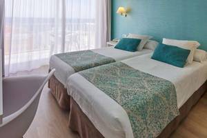 Doppelzimmer mit Meerblick im BQ Apolo Hotel, mit zwei Betten, blauen Kissen und einem Blick auf das Meer.