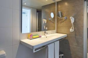 Ein Badezimmer im BQ Apolo Hotel mit einer Dusche, einem Waschbecken und einem Spiegel.