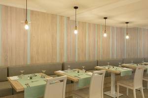 Innenraum des HSM Linda Playa Hotel Restaurants mit Holzwänden, blauen Streifen, und Tischen mit grünen Tischdecken.