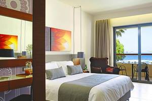 Hotelzimmer im Atlantica Kalliston Resort mit Meerblick, Bett, Möbel und Kunstwerke.