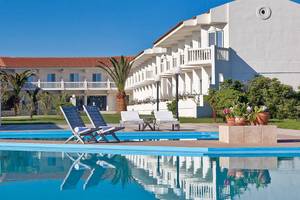 Außenpool des Mrs Chryssana Beach Hotels mit weißen Liegestühlen und Gebäuden im Hintergrund