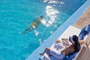 Frau am Rand des Pools von Mrs Chryssana Beach Hotel liest ein Buch