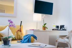 Helles Zimmer im Dreams Flora Resort & Spa mit einem Sofa, Tisch, Lampe und Fernseher.
