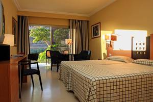 Innenansicht eines Zimmers im LIVVO Costa Taurito Hotel mit zwei Betten, Schreibtisch und Sitzbereich.