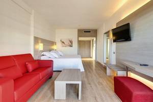 Hotelzimmer im Barcelo Margaritas mit rotem Sofa, Tisch, Bett und Fernseher.
