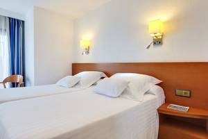 Doppelzimmer im Barcelo Margaritas Hotel mit zwei Betten, weißen Kissen, Nachttischen und Wandlampen.