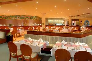Innenansicht des Restaurants im DoubleTree by Hilton Sharks Bay Resort mit gedeckten Tischen und Stühlen.