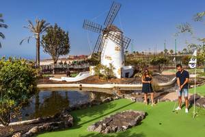 Golfplatz mit einem Paar, das vor einer Mühle spielt, im Freien.