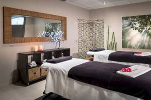 Spa-Behandlungsraum im Barcelo Fuerteventura Mar Hotel mit zwei Behandlungstischen, Kerzen und einem großen Gemälde.