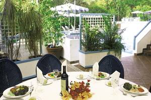 Essen im Garten des Karibea Sainte Luce Hotels mit Tisch, Tellern und Pflanzen.