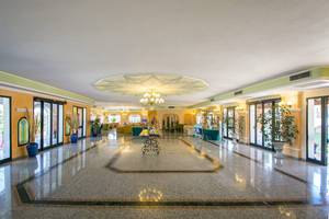 Empfangsbereich des Club Hotel Marina Beach mit hellem Innendesign, großen Fenstern und Dekorationspflanzen.