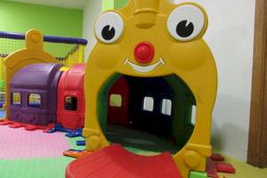 Kinderspielplatz im AX Odycy Hotel mit bunten Spielzeugzügen und einem großen gelben Spielzeugzug.