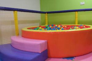 Spielplatz im AX Odycy Hotel mit einem großen orangen Kugelbad gefüllt mit bunten Bällen.