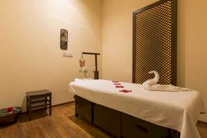 Massageraum im Seashells Resort at Suncrest mit einem Behandlungstisch, Rosenblättern und einem Tisch mit Blumen.