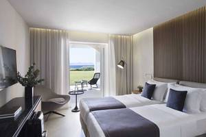 Doppelbettzimmer im Neptune Luxury Resort mit Blick auf den Garten und das Meer.