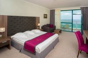 Hotelzimmer im Marina Grand Beach Hotel mit Meerblick, Bett, Schreibtisch und Sofa.