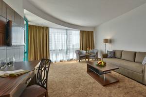 Hotelwohnbereich mit Sofa, Tisch, Stühlen und Fernseher.