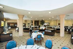 Innenansicht des Restaurants im Marina Grand Beach Hotel mit blauen Stühlen und Tischen, Buffet und Säulen.