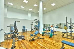 Fitnessstudio im Marina Grand Beach Hotel mit verschiedenen Trainingsgeräten und einem großen Spiegel.