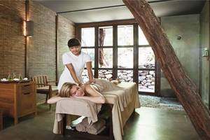Eine Frau liegt entspannt auf einer Massageliege im Hillside Beach Club und wird von einer Therapeutin massiert.