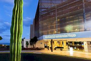 Vorderansicht des Barcelo Lanzarote Active Resort mit Kakteen vor dem Gebäude und Meer im Hintergrund