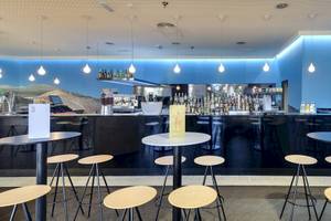 Bar im Barcelo Lanzarote Active Resort Hotel mit Barhockern, Tischen und einer Bar im Hintergrund.