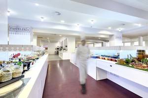Restaurantbereich des Barcelo Lanzarote Active Resort mit einer Theke voller Speisen und einem Koch in weißer Kleidung, der sich entfernt.