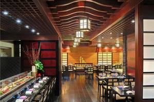 Innenansicht des Sushi-Restaurants im Tivoli La Caleta Tenerife Resort mit Holztischen, Stühlen und traditioneller Beleuchtung.