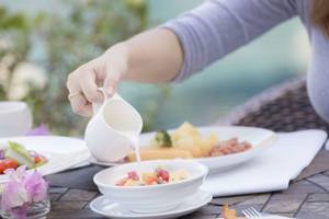 Frühstückstisch im Beyond Resort Krabi mit Schüssel, Tellern, Milch und Blumen.