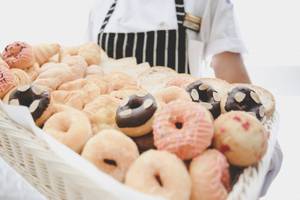 Ein Korb voller Gebäck, darunter Donuts und Croissants, wird von einem Mitarbeiter im Hotel Beyond Resort Krabi präsentiert.