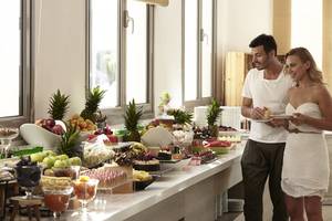Paar vor einem Buffet-Tisch im Louis St. Elias Resort & Waterpark mit vielen verschiedenen Speisen