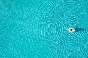 Frau im Pool von oben gesehen, die auf einem Schwimmring liegt.