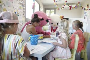 Im Louis St. Elias Resort & Waterpark Kinderclub unterhalten sich Hello Kitty und ein Mitarbeiter mit Kindern beim Malen.