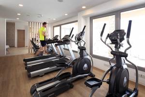 Fitnessraum im Louis St. Elias Resort & Waterpark mit mehreren Cardiogeräten und einem Mann, der läuft.