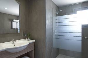Badezimmer im Louis St. Elias Resort & Waterpark mit Waschbecken, Spiegel und Dusche.
