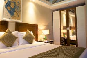 Hotelzimmer im Ellaidhoo Maldives by Cinnamon mit Bett, Kissen, Lampen und Gemälde an der Wand.