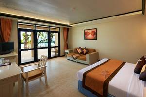 Innenansicht eines Zimmers im Ellaidhoo Maldives by Cinnamon mit Meerblick, Doppelbett, Wohnzimmerbereich und Fernseher.