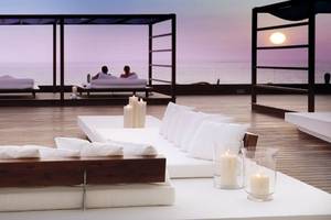Loungebereich des H10 Gran Tinerfe Hotels mit Blick auf den Ozean und zwei Personen, die sich entspannen.
