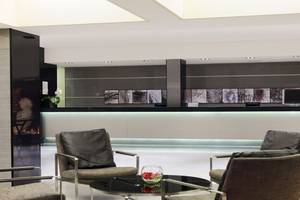 Lobby-Lounge-Bereich des H10 Gran Tinerfe Hotels mit Sitzmöbeln, Empfangstresen und zentralem Tisch.
