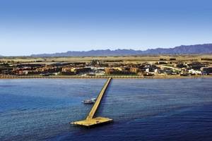 Luftaufnahme des Stella Gardens Resort & Spa Makadi Bay mit einer langen Brücke und einem Boot im Wasser.