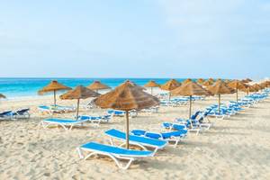 Strandszene im Oasis Belorizonte Hotel mit vielen Sonnenliegen und Sonnenschirmen.