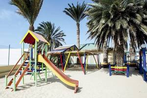 Spielplatz im Oasis Belorizonte Hotel, bunte Spielgeräte unter Palmen