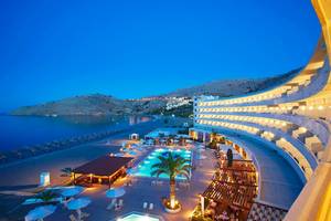 Lindos Bay Hotel von der Seite bei Nacht, mit Blick auf den Strand und die Berge.