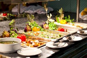 Buffet mit mehreren Gerichten im El Mouradi Djerba Menzel Hotel, darunter Salate, Fleisch und Suppe.