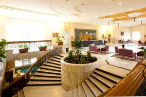 Lobby des El Mouradi Djerba Menzel Hotels mit zentraler Pflanze und Treppen.