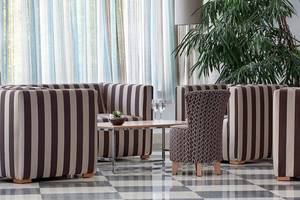 Lobby-Lounge des Lindos Bay Hotels mit gemusterten Sesseln und Tischen.