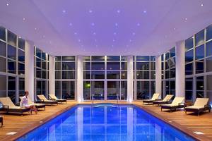 Ein Innenpool im Lindos Bay Hotel mit Lounge-Sesseln und einer Frau, die entspannt sitzt.