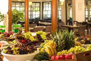 Frühstücksbuffet im Silva Beach Hotel mit verschiedenen Früchten wie Trauben, Äpfeln, Bananen und Melonen.