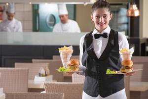 Eine Mitarbeiterin im Silva Beach Hotel serviert Essen in einer Speisekarte.